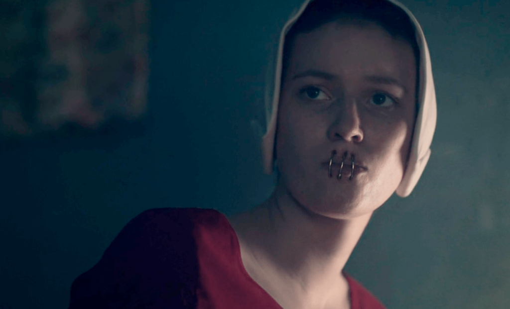 Aia punida com grampos nos lábios para manter o silêncio na 3ª temporada de The Handmaid's Tale.